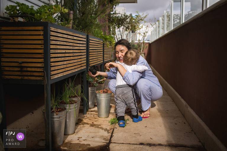 Foto de Adriana Costa premiada internacionalmente pela Associação FPJA (Family Photojournalist Association) da mãe abraçando o filho que está começando a andar