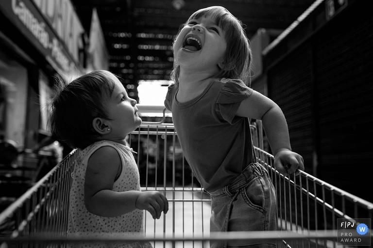 Foto de Adriana Costa das crianças se divertindo no carrinho do mercado, premiada internacionalmente pela Associação FPJA (Family Photojournalist Association)