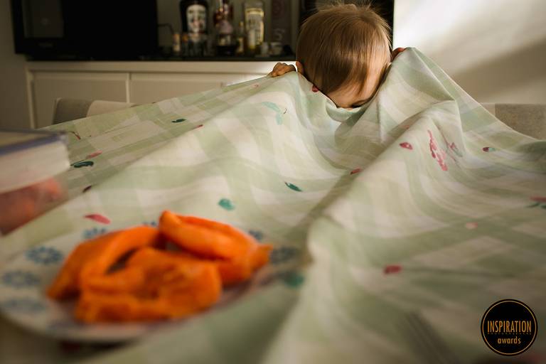 foto de Adriana Costa premiada pela Inspiration Family Awards de uma criança escondendo o rosto na toalha de mesa