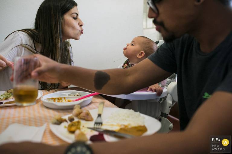 Adriana Costa  recebeu o prêmio internacional pela Associação FPJA (Family Photojournalist Association) na foto da mãe mandando beijo para a filha e a filha fazendo careta, na mesa de almoço, com o pai