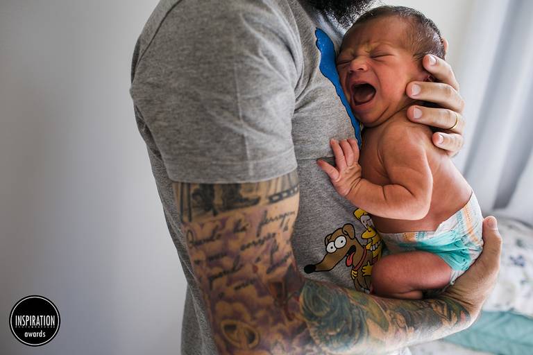 Adriana Costa foi premiada pela Inspiration Family Awards com uma foto do pai tatuado, vestido  com uma camisa estampada com o cachorro dos Simpsons fazendo careta, abraçando seu bebê chorando