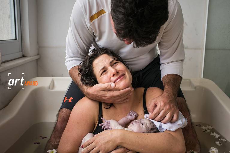 Foto de Adriana Costa premiada pela fineart association do primeiro colo, do primeiro olhar entre pais e filha após o nascimento