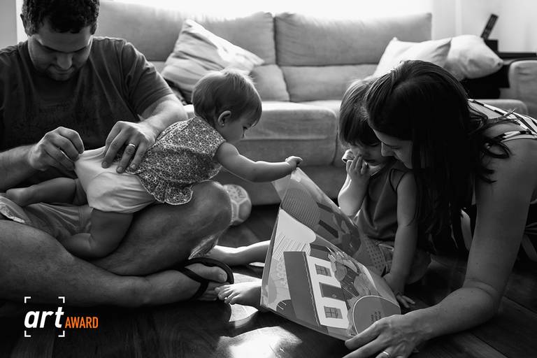foto de Adriana Costa sobre família interagindo e pai olhando a fralda da filha, premiada pela Fineart Association