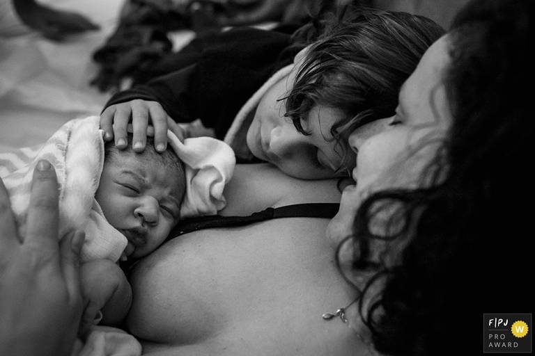 Foto de Adriana Costa premiada pela Associação FPJA de uma mãe descansando após um trabalho de parto domiciliar com os seus dois filhos