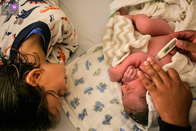 Foto de Adriana Costa do menino observando seu irmão recém-nascido recebendo sua primeira avaliação foi premiada pela Associação FPJA