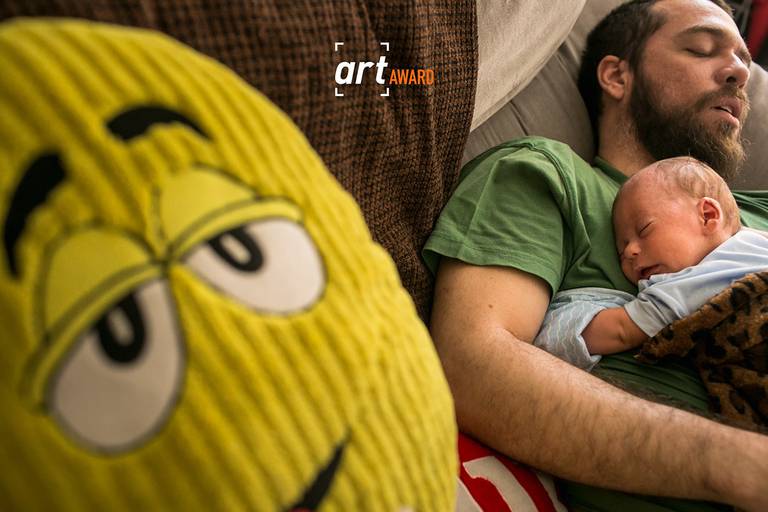 Foto de Adriana Costa premiada pela fineart association de um bebê dormindo sobre a barriga de um pai que também caiu no sono