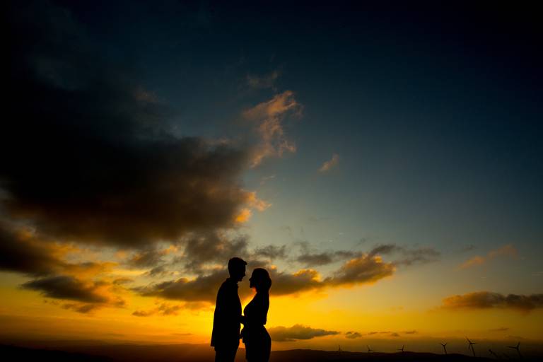 silhueta de casal de namorados recortada no horizonte com por-de-sol