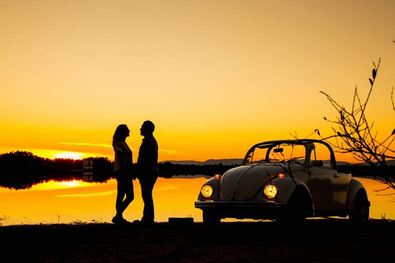 casal de namorados acompanhados de carro clássico no pôr do sol