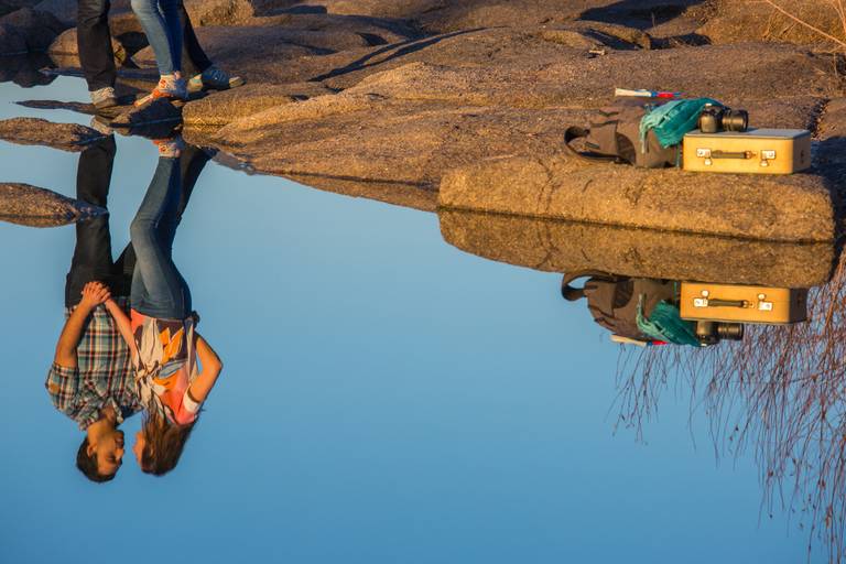 reflexo do casal numa poça de água e ao lado material pertencente ao fotografo