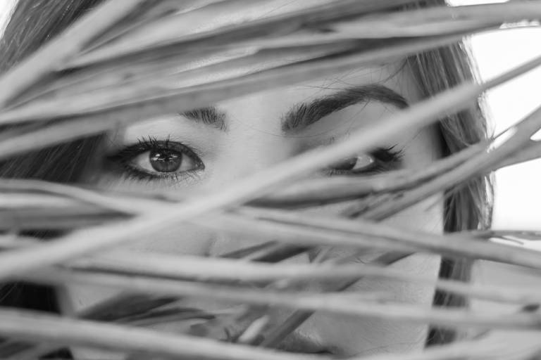 foto em preto e branco de olhos de mulher japonesa atrás de galho de árvore