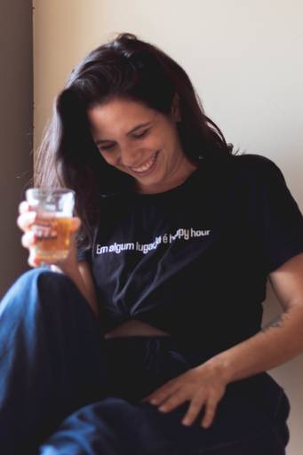 mulher dando risada com copo de cerveja na mão em ensaio feminino interno