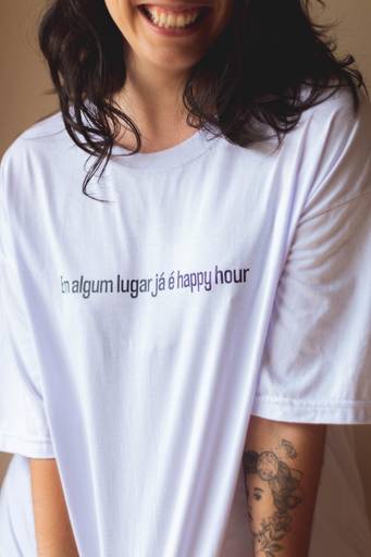 mulher de camiseta branca sorrindo pra câmera, em sessão de fotos internas