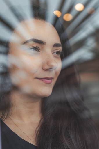 imagem de rosto de mulher olhando para frente com reflexo do vidro