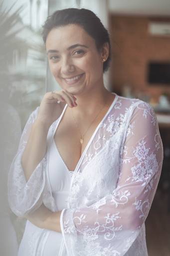 foto de mulher de robe branco com a mão no queixo, sorrindo para a câmera
