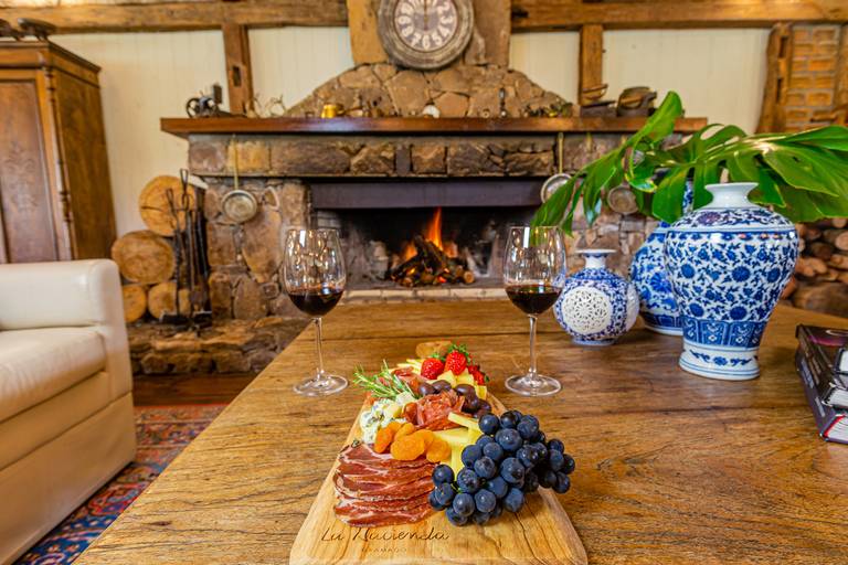 Tabua de frios, vinho e uma lareira aconchegante no Hotel La hacienda. 