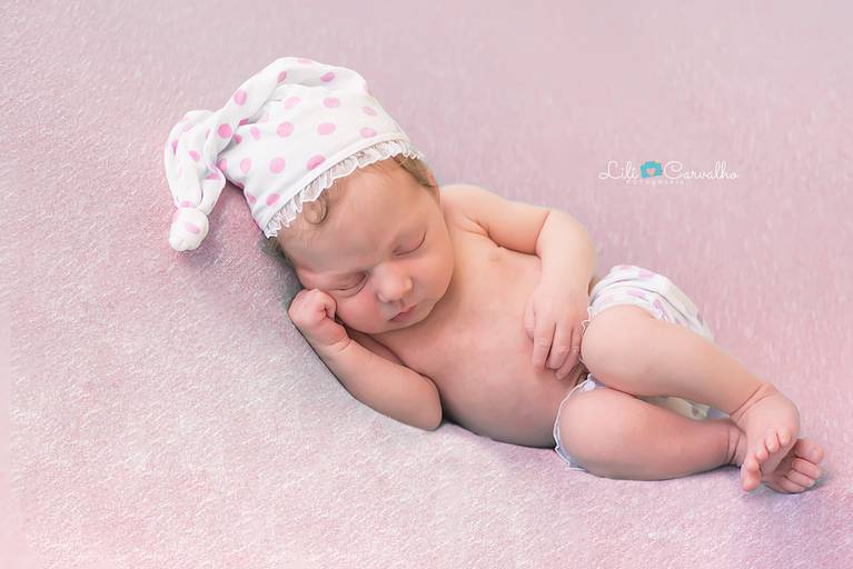 foto de bebe em fundo rosa, de touca, dormindo 