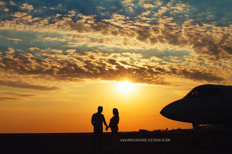 Silhueta do casal e do avião ao lado, com um lindo por-do-sol ao fundo