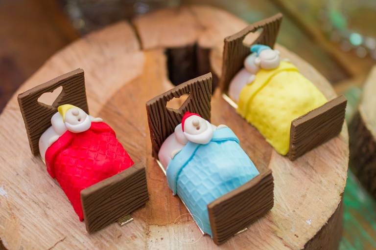 Docinhos inspirados nos anões da branca de neve, deitadinhos em uma caminha e com cobertorezinhos