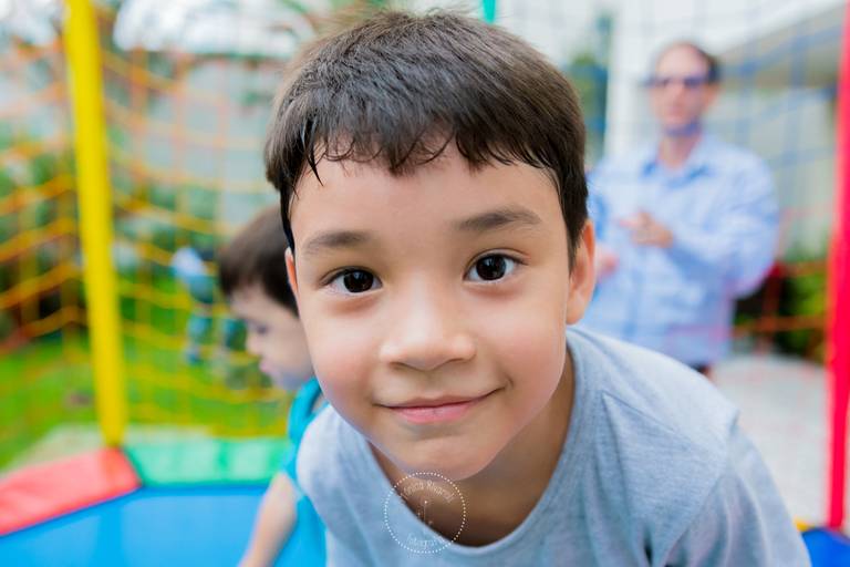 Criança brincando no pula-pula e olhando para a câmera 