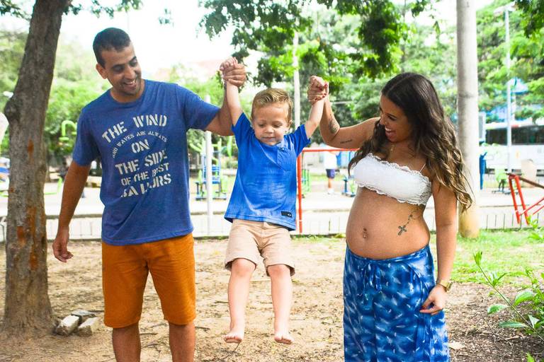 Gestante e o Marido levantando o filho mais velho em um parque no Rio de Janeiro