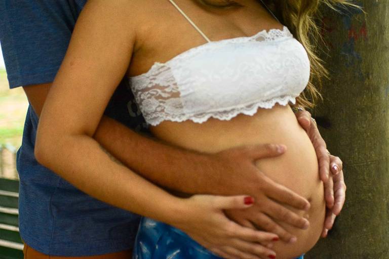 Close Up das mãos da Gestante e do Marido na barriga dela. 