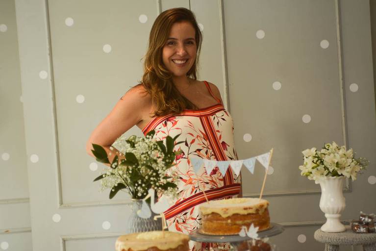 Gestante posa feliz em frente a decoração do seu Chá de Bebê