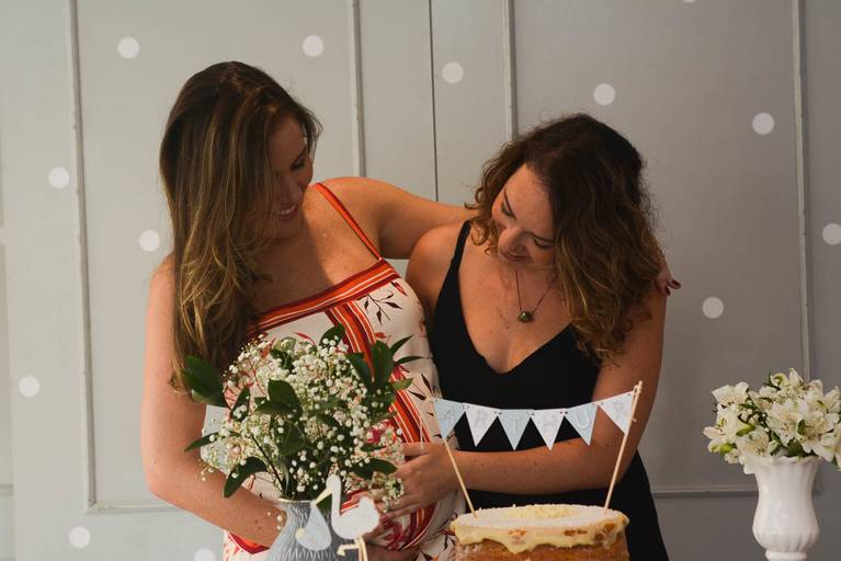 Gestante e a irmã olham para a barriga dela, felizes em seu Chá de Bebê