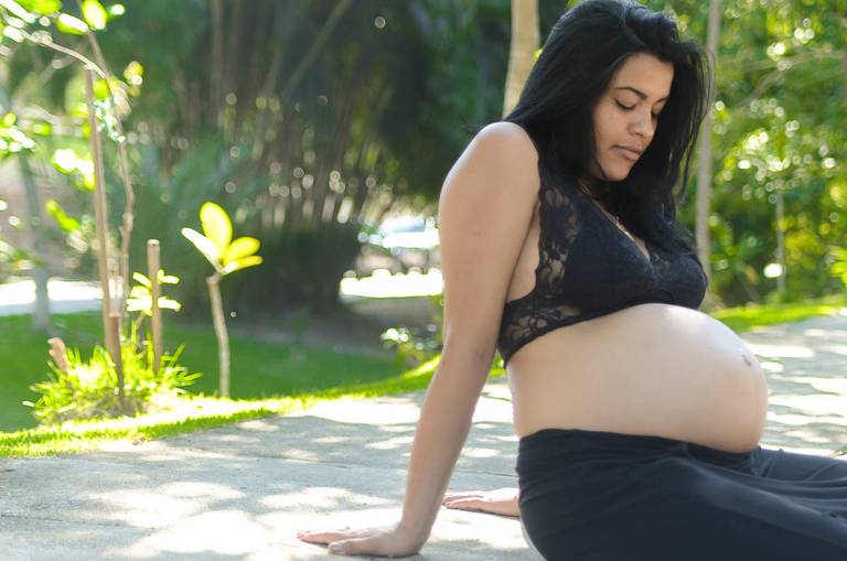 Gestante olhando a barriga em um parque no Rio de Janeiro
