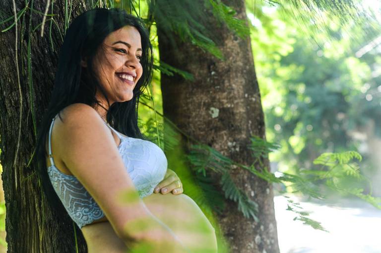Gestante Sorrindo ao lado de uma árvore no Rio de Janeiro