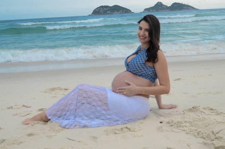 Grávida feliz sorrindo em frente ao mar no Quebra Mar na Praia da Barra da Tijuca no Rio de Janeiro