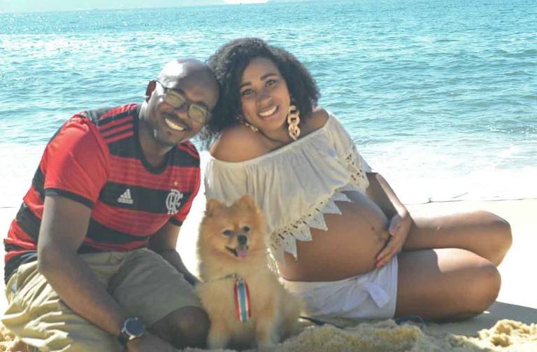 Casal Grávido sorrindo com um cachorrinho em frente ao mar  na Praia Vermelha no Rio de Janeiro