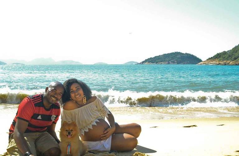 Casal Grávido sorrindo com um cachorrinho em frente ao mar  na Praia Vermelha no Rio de Janeiro