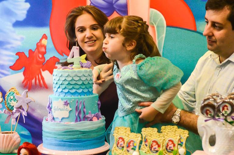 Menina assopra a velinha do bolo da sua festa infantil de aniversário da Pequena Sereia na Quintal Tijuca no Rio de Janeiro