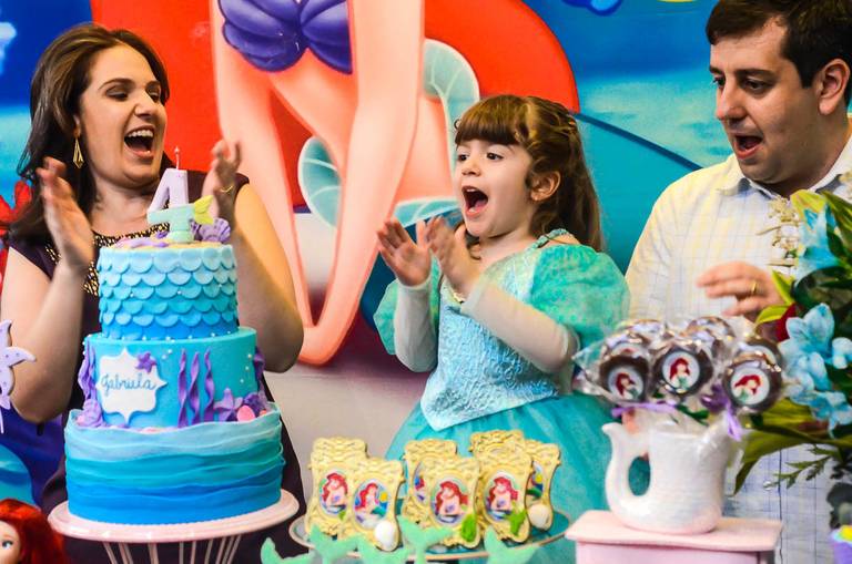 Menina cantando parabéns para você com os pais em sua festa de aniversário infantil da Pequena Sereia na Quintal Tijuca no Rio de Janeiro