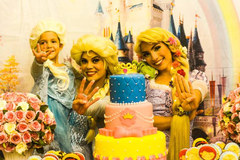 Menina posa com a Elsa de Frozen e a Rapunzel de Enrolados da Disney em frente a sua decoração de Princesas na sua festa infantil de aniversãrio na Barra da Tijuca no Rio de Janeiro