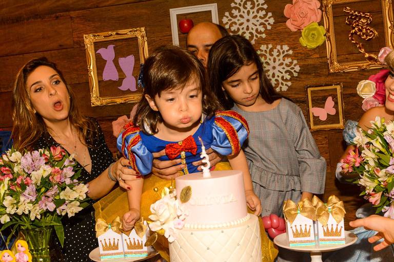 Menina vestida de Branca de Neve assopra a velinha do seu bolo de aniversário da sua festa infantil das Princesas da Disney na Quintal Aventura em Botafogo no Rio de Janeiro