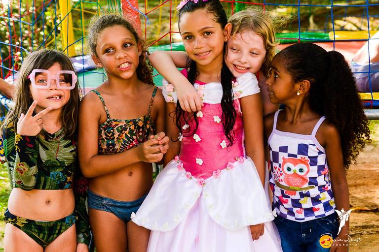 Amigas abraçadas em frente a um pula pula em uma festa infantil 