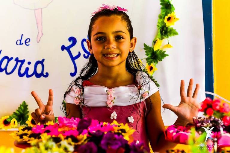 Menina Sorrindo mostrando que está completando 7 anos em sua festa infantil com tema de Jardim
