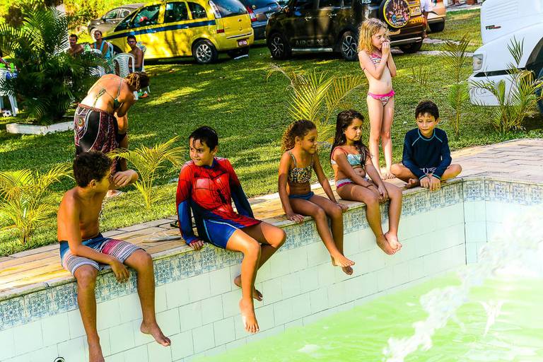 Crianças esperando a água preencher a piscina em uma festa de aniversário infantil