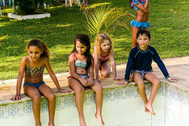 Crianças sentadas na beira da piscina