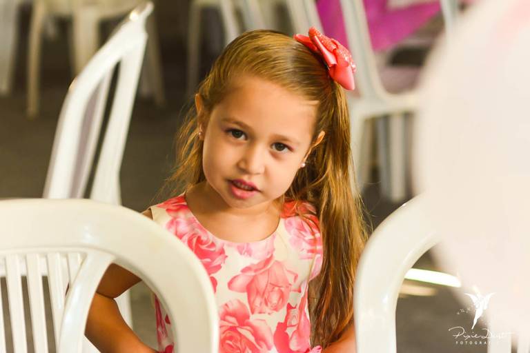 Menina olhando para a câmera no meio de cadeiras em sua festa de aniversário infantil