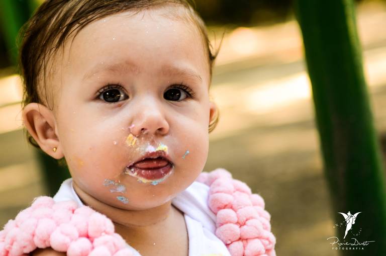 Bebê lambuzada depois de provar seu bolo de aniversário