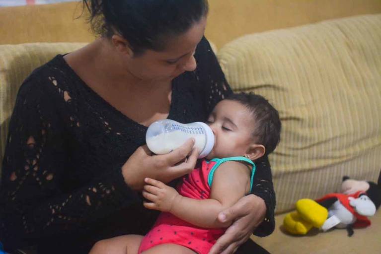 Bebê de seis meses tomando fórmula de leite na mamadeira e já dormindo no colo da mãe no Rio de Janeiro