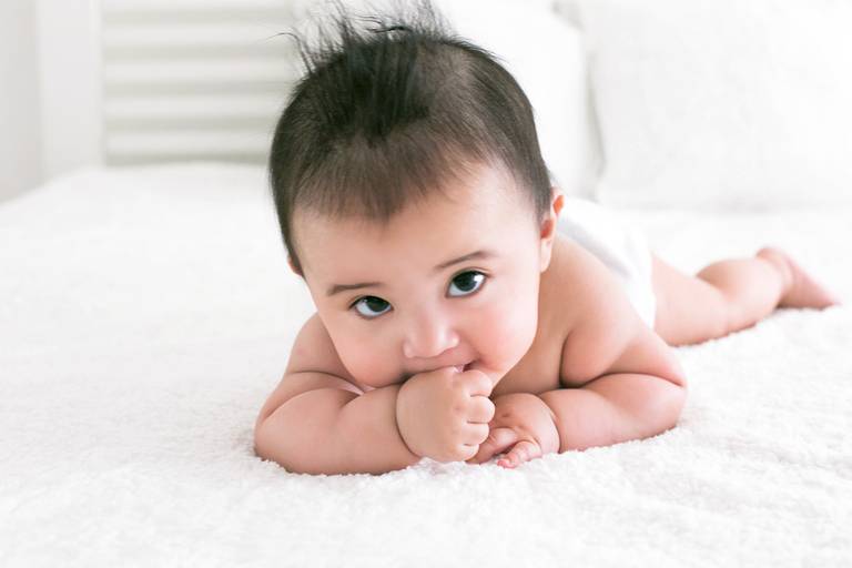 bebe de bruços na cama 