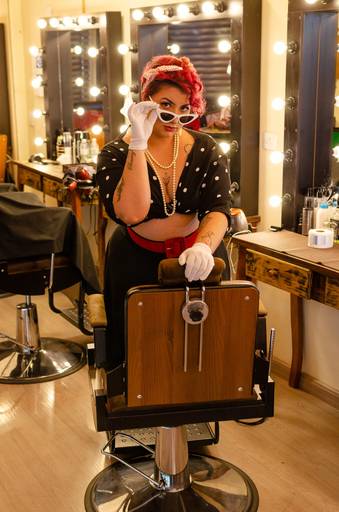 Ensaio sensual  PinUp numa barbearia com saia preta, cropped  e óculos branco.