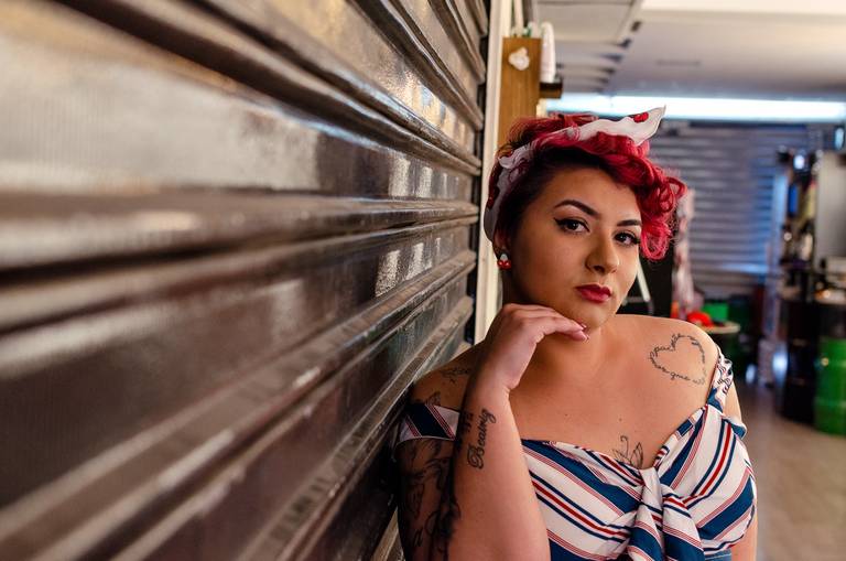 Ensaio sensual  PinUp numa barbearia com saia preta e top estampado.