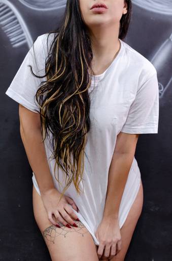 Ensaio fotográfico sensual da Bia de camisa branca, mostrando a boca. Realizado em uma barbearia.
