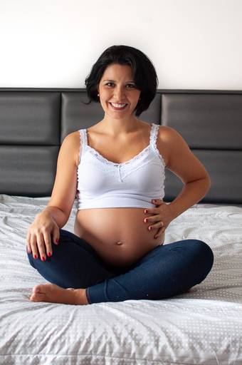 gestante sentada de frente e sorrindo