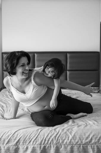 criança brincando com a mãe em cima da cama