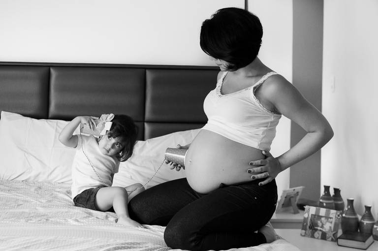 criança brincando de ouvir o bebê na barriga da gestante